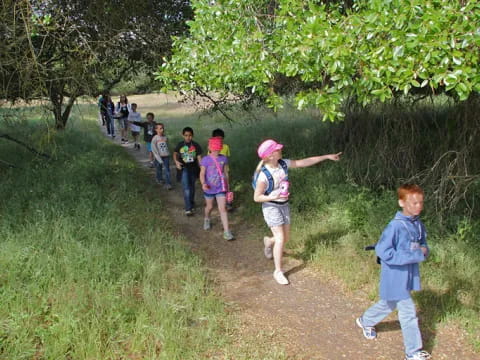 a group of people walking on a path in a grassy area
