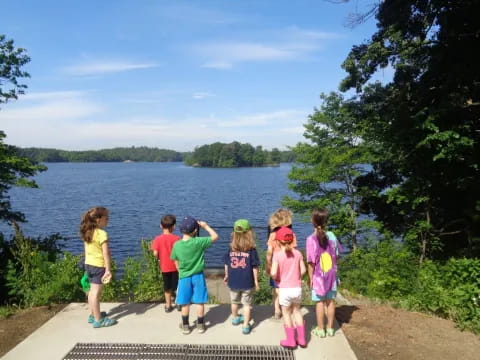 a group of children standing on a path by a body of water