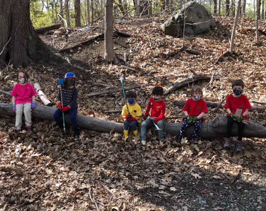 a group of kids sitting on a log in the woods