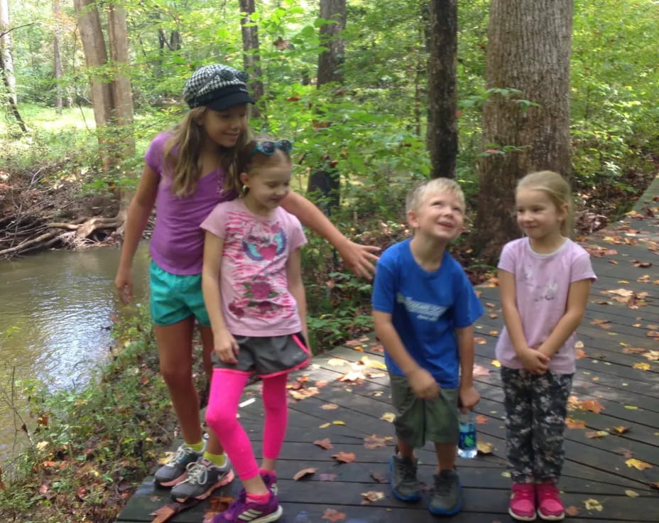 a group of children standing on a wooden bridge over a river