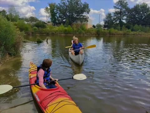 two kids in kayaks on a river