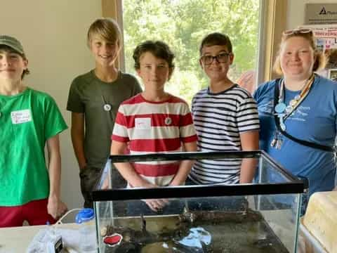 a group of people standing around a table with a fish in it