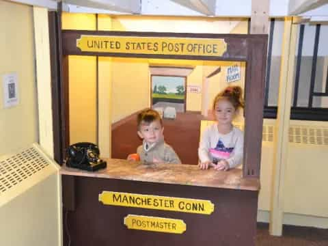 a couple of children sitting at a desk in a room