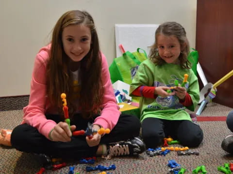 a couple of girls sitting on the floor with toys