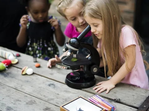 a group of children playing with a microscope
