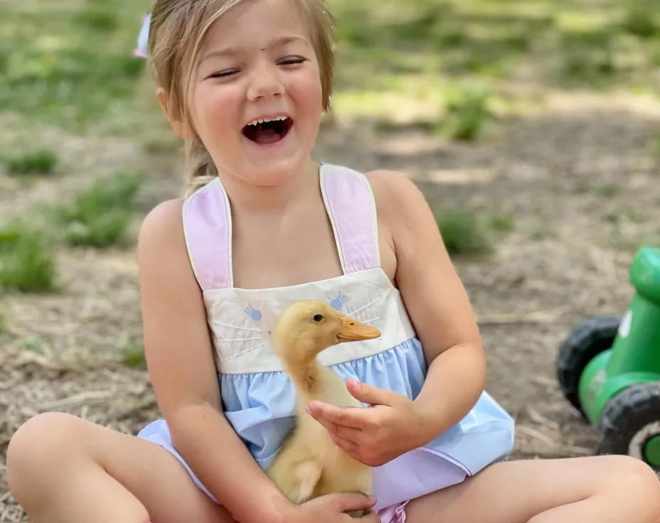 a girl sitting on a pink toy