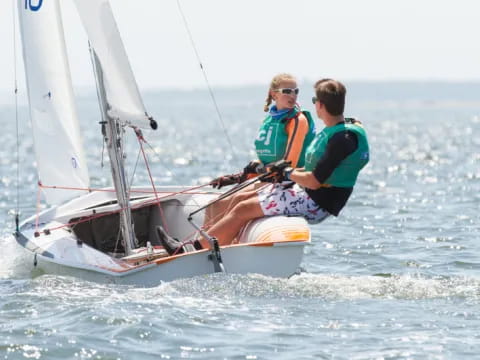 a couple of people on a sailboat in the water