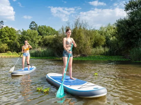 a couple of women on paddle boards in a river