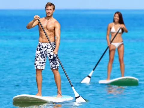 a man and woman paddle surfing