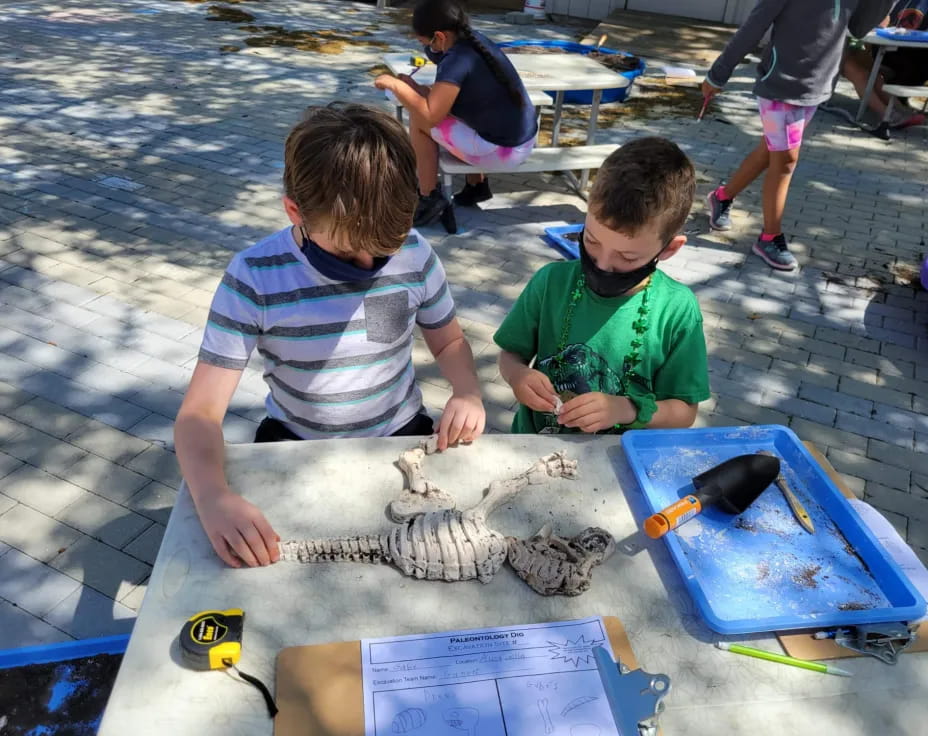 a couple of boys sitting at a table with a fish