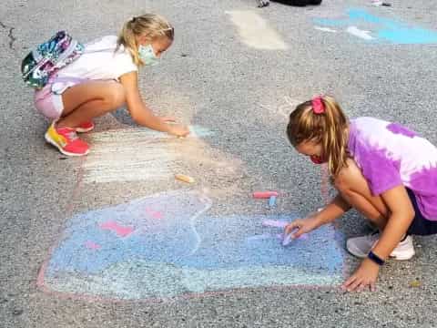 a couple of girls painting on the ground