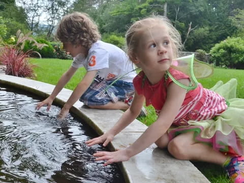 a couple of children playing in a pond