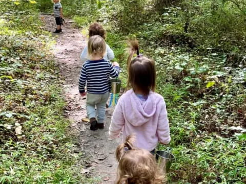 a group of children walking on a path in the woods