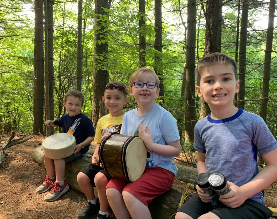 a group of kids holding drums in the woods