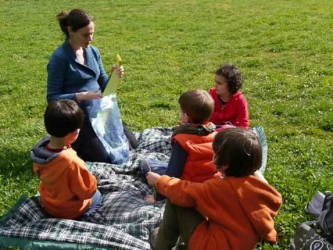 a person and several children sitting on the grass