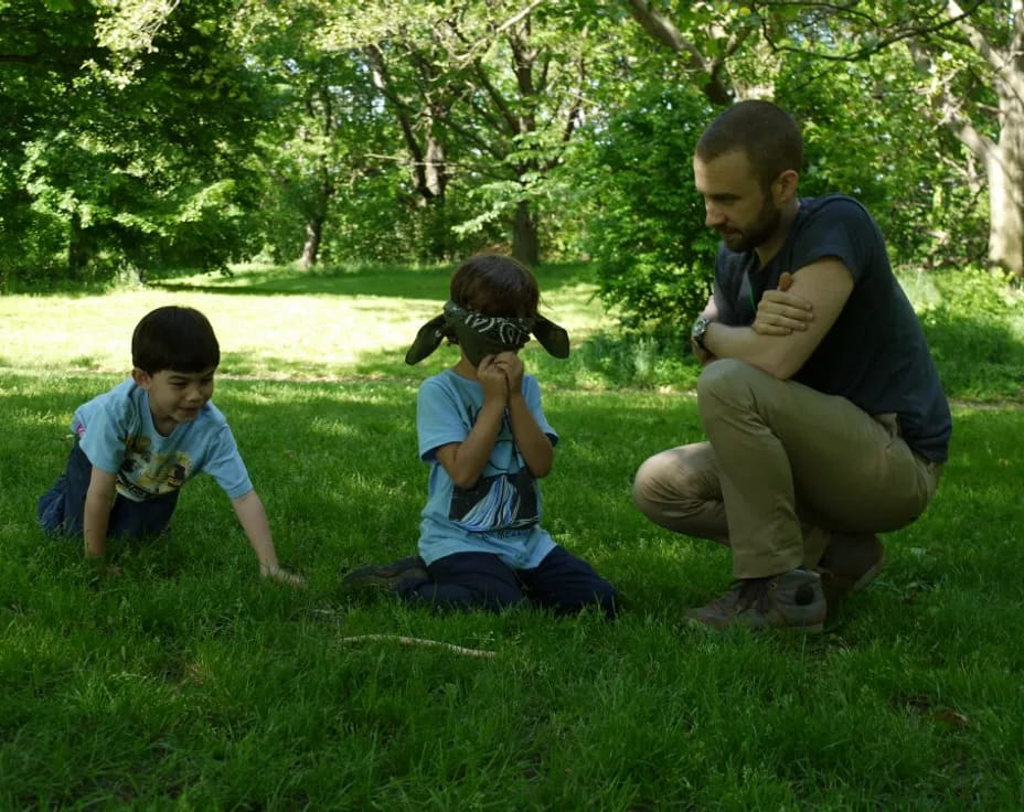 a person and two boys sitting in the grass with a camera