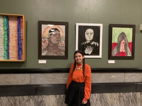 a person standing next to several paintings