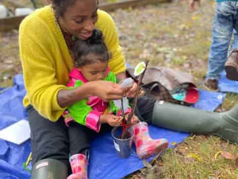 a person and a child sitting on a blanket outside