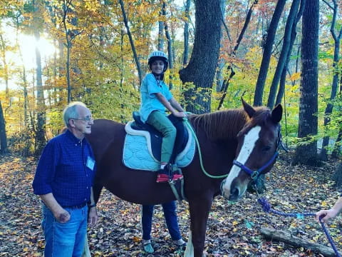 a person and a child riding a horse in the woods