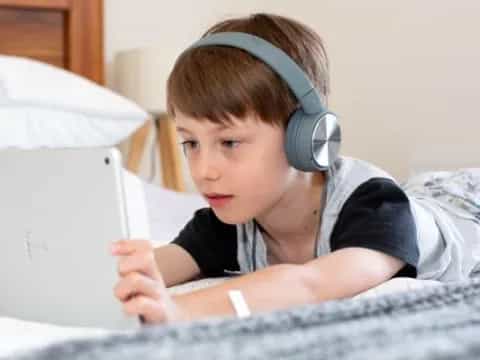 a young boy wearing headphones and reading a book
