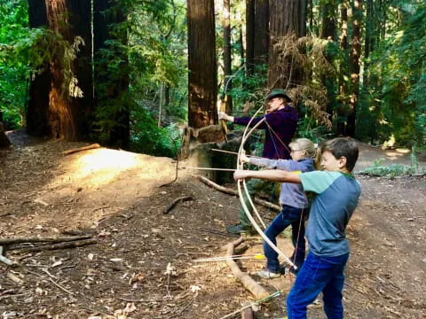 a group of people holding a bow and arrow in the woods