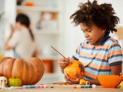 a young girl painting a pumpkin