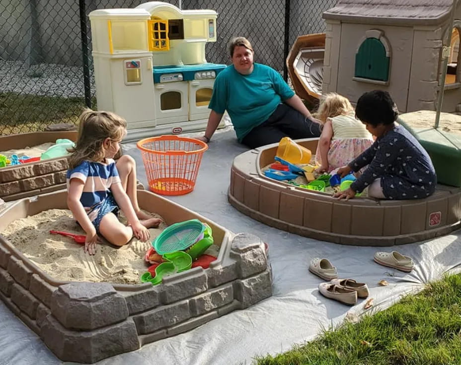 a person and children playing in a sandbox