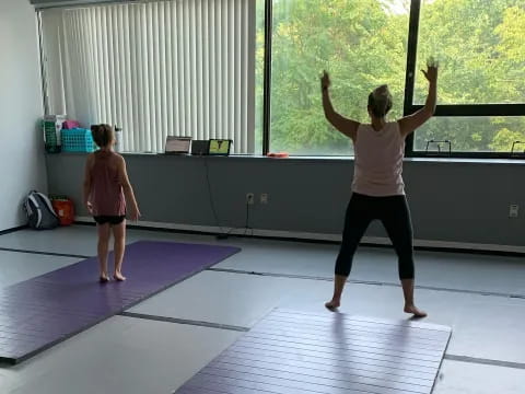 a woman and a girl exercising in a room with a window