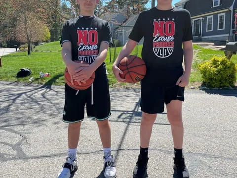 two boys wearing black shirts and holding a basketball