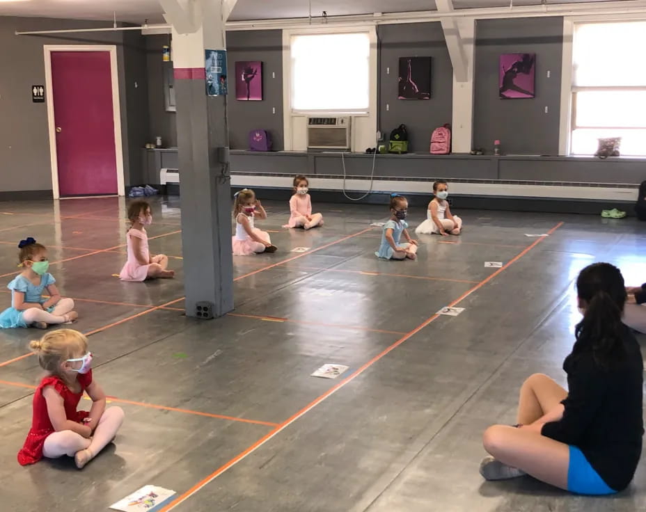 a group of children sitting on the floor in a gym