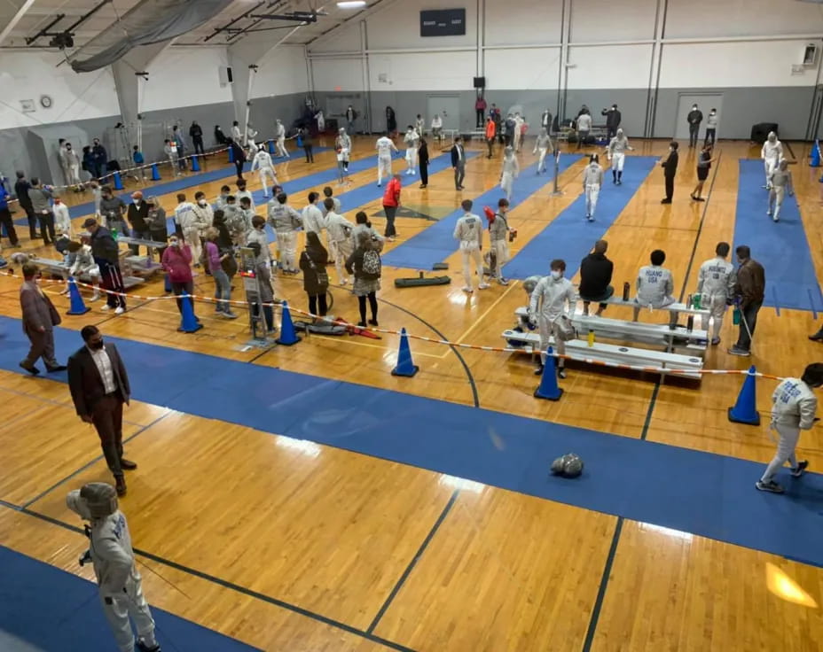 a group of people on a blue mat in a room with a blue floor and a person standing