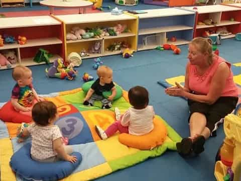 a person and several children sitting on a colorful mat