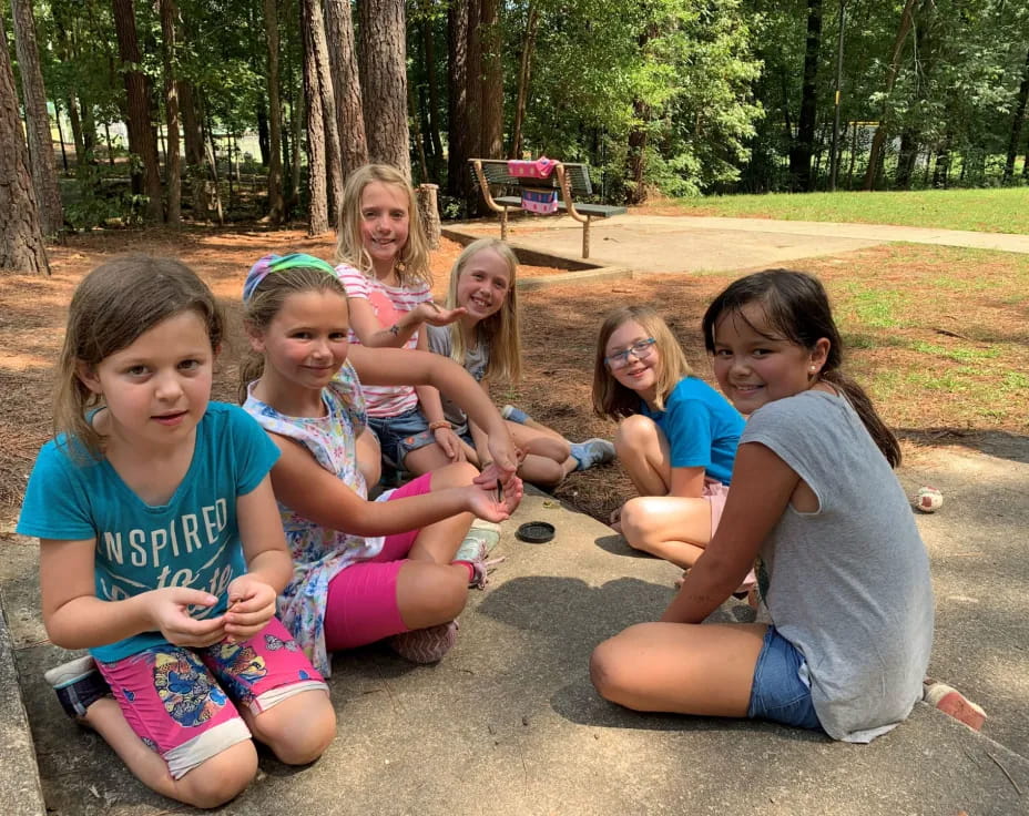 a group of girls sitting on the ground outside