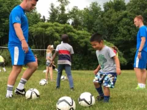 a person and a couple of kids playing football