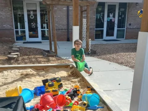 a boy sitting on a ledge with a pile of toys in front of him