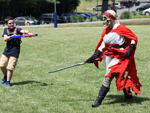 a person in a garment holding a sword and a boy in a red garment