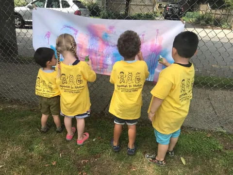 a group of children in yellow t-shirts standing in front of a banner