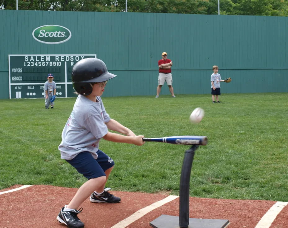 a kid hitting a ball with a baseball bat