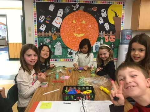 a group of children sitting at a table with a board game