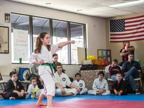 a girl doing a karate move in front of a group of people