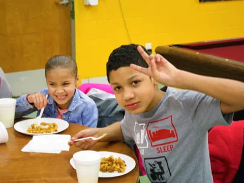 a couple of boys eating at a table