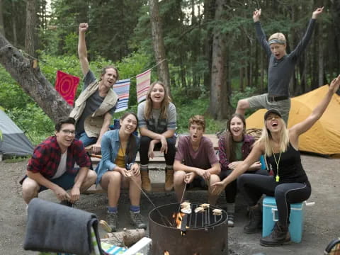 a group of people sitting on a fire pit in the woods