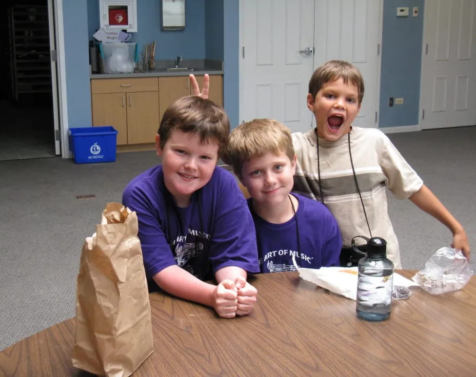 a group of boys sitting at a table with a bag of chips