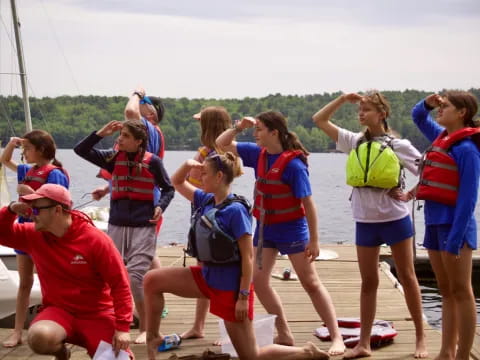 a group of people wearing life vests and standing on a dock