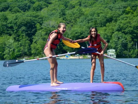 a couple of girls on a paddle board in the water