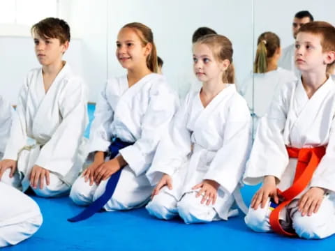 a group of people in white karate uniforms sitting on the floor