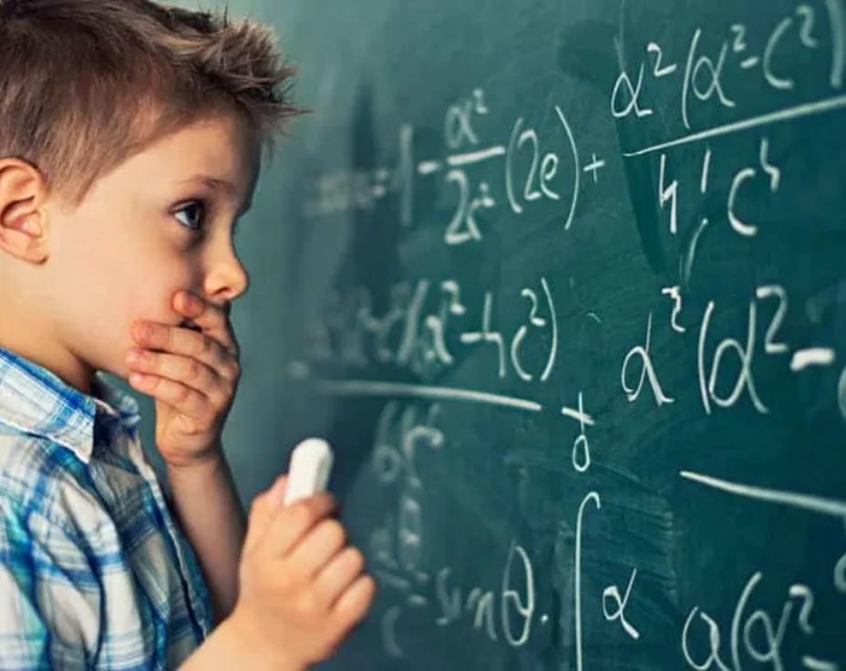 a young boy writing on a chalkboard