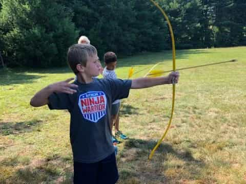 a group of boys holding bows and arrows in a field