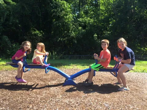 a group of children sitting on a blue trampoline in a park