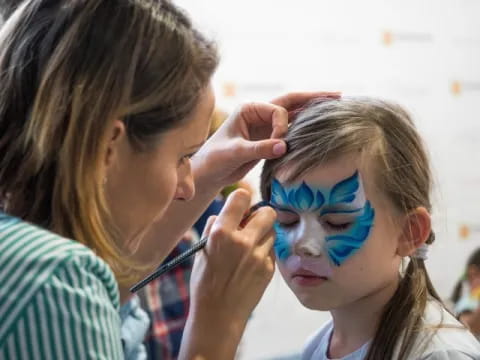 a woman painting a girl's face